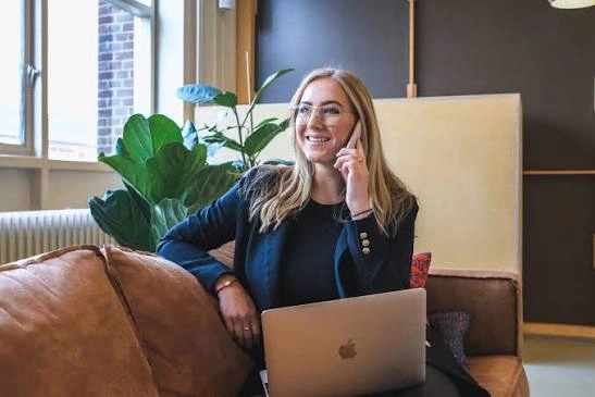 Zelfstandig coach in gesprek via de telefoon, met een laptop op schoot