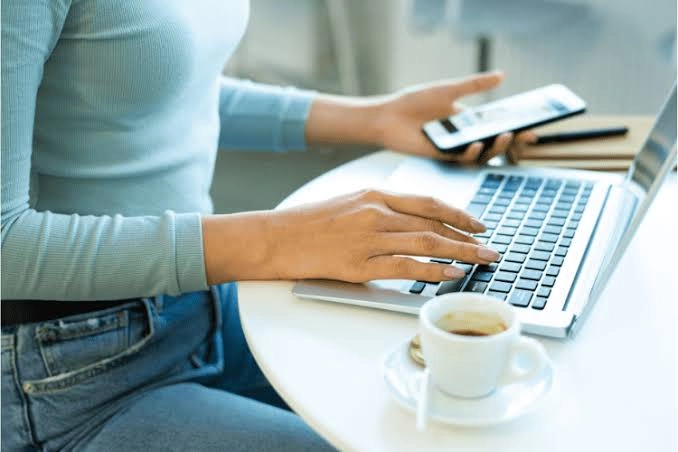 Freelancer werkt op een laptop met een telefoon in de hand