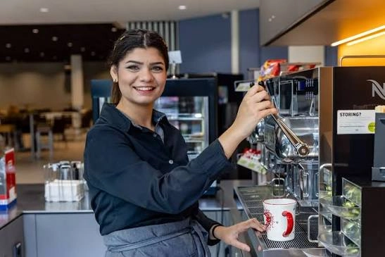 Horecamedewerker zet koffie achter de bar van een zaak