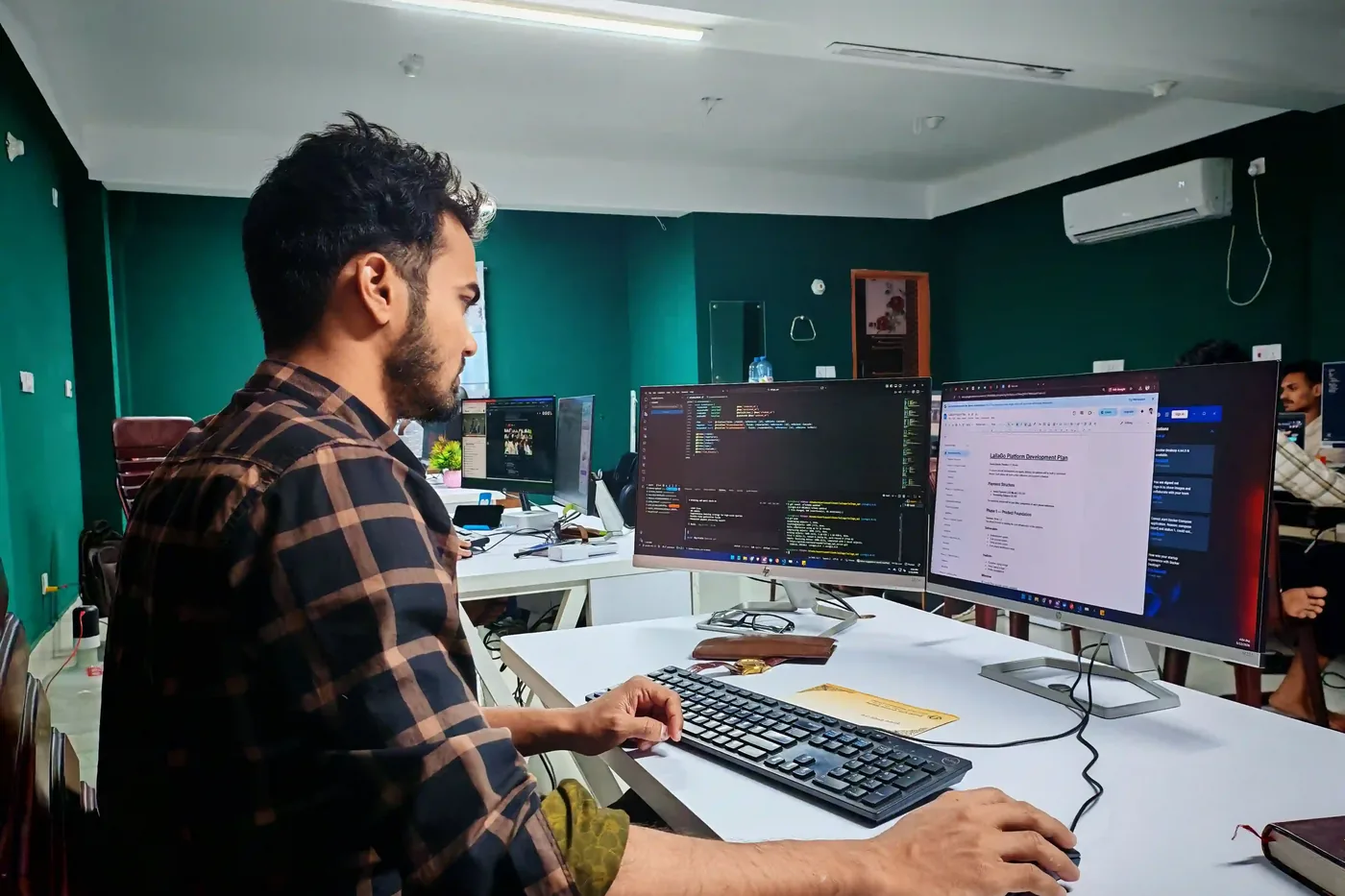 Softwareontwikkelaar werkt met code op twee schermen