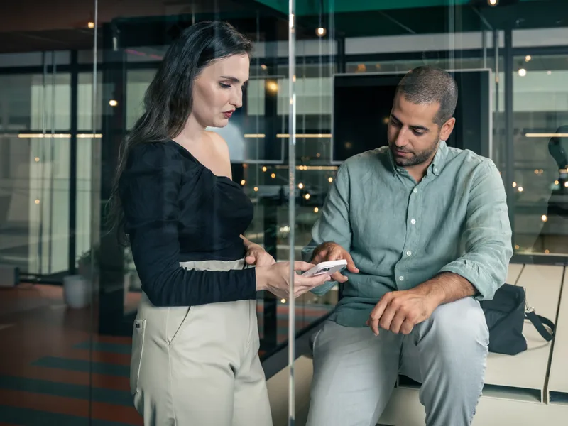 Twee ondernemers bekijken samen een telefoon in een kantoor